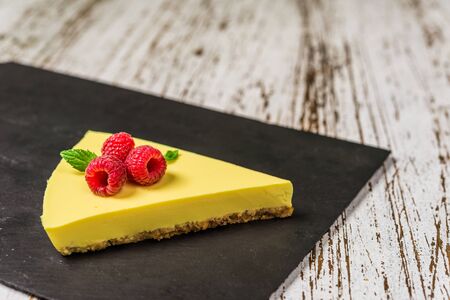 Lemon cheesecake with raspberries, mint, and jam against white wood backgroundの写真素材