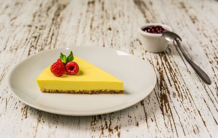 Lemon cheesecake with raspberries, mint, and jam against white wood background.の写真素材