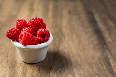 Fresh colorful organic raspberry fruit against wooden background.の写真素材