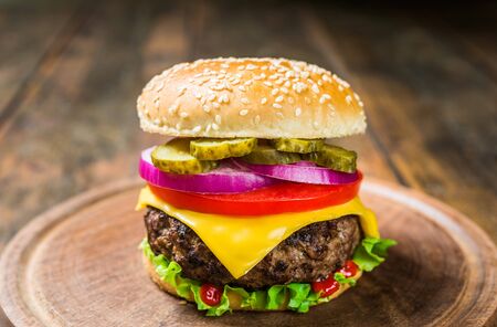 Cheese burger with cheese against wooden background. Tasty fast food.の写真素材