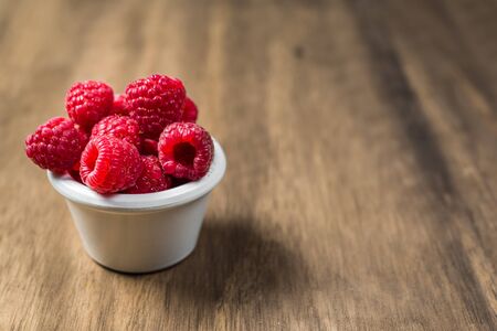 Fresh colorful organic raspberry fruit against wooden background.の写真素材