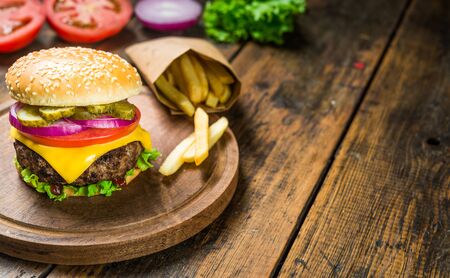 Cheese burger and french fries against wooden background. Tasty fast food.の写真素材