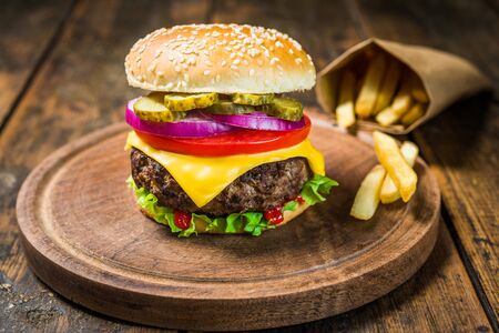 Cheese burger and french fries against wooden background. Tasty fast food.の写真素材
