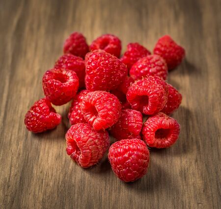 Fresh colorful organic raspberry fruit against wooden background.の写真素材