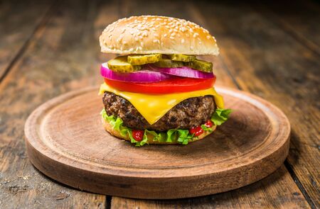 Cheese burger with cheese against wooden background. Tasty fast food.の写真素材