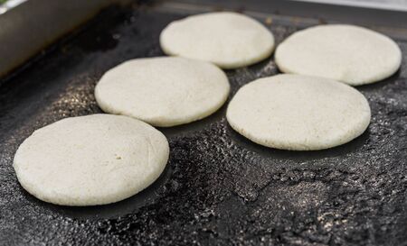 Uncooked arepas, traditional Venezuelan corn patties, at a street food market.