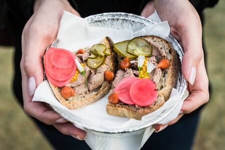 Tapas sandwiches with leberwurst, pickles, and flowers at a street food market.の写真素材