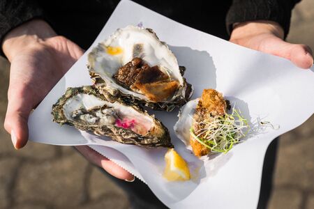 Close up of raw, fried, and smoked gourmet oysters at a street food market.の写真素材