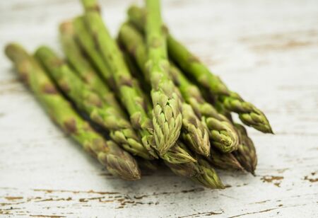 Close up of a bunch of asparagus against white wooden background.の写真素材