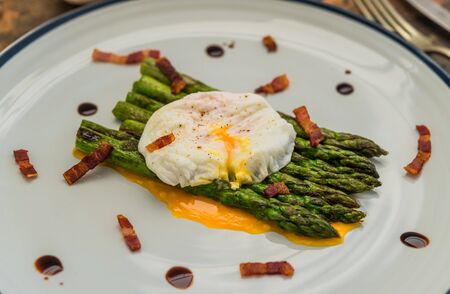 Food photography of a poached egg with asparagus, and crispy bacon.の写真素材