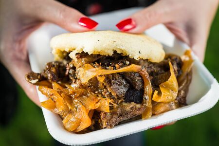 An arepa with lamb meat and caramelized onion at a street food market.の写真素材