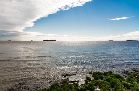 Wide angle photo of shore and colorful shiny sea ocean on a sunny dayの写真素材