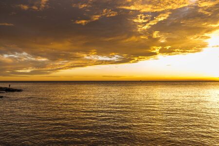 Fisherman catching fish at the shore with beautiful sunset sky.の写真素材