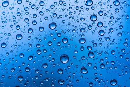 Water drops on glass window blue background after the rain in the autumn fallの写真素材