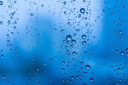 Water drops on glass window blue background after the rain in the autumn fallの写真素材