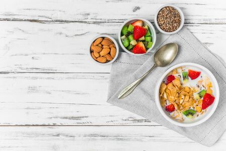 Bowl of breakfast cereals with milk, strawberry, kiwi, almonds, and seedsの写真素材