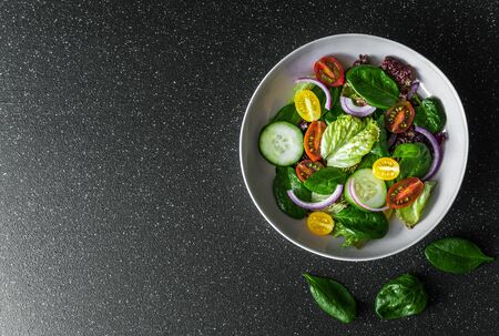 Top view of greens vegetable salad bowl with lettuce, spinach, and tomatoes.の写真素材