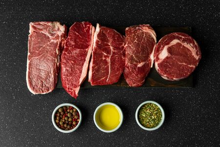Selection of raw beef meat food steaks against black stone backgroundの写真素材