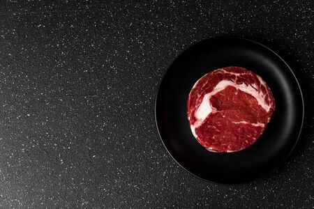 Raw prime beef rib eye meat food steak against black stone backgroundの写真素材