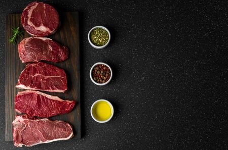 Selection of raw beef meat food steaks against black stone backgroundの写真素材