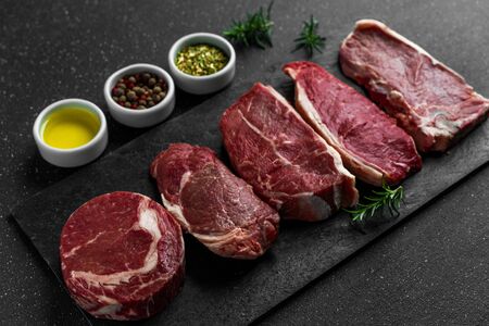 Selection of raw beef meat food steaks against black stone backgroundの写真素材