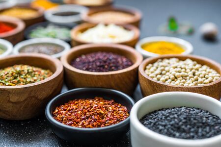 Variety of colorful spices, herbs, and seeds on black stone backgroundの写真素材