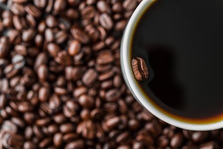 A coffee bean floating in a cup of black coffee.の写真素材