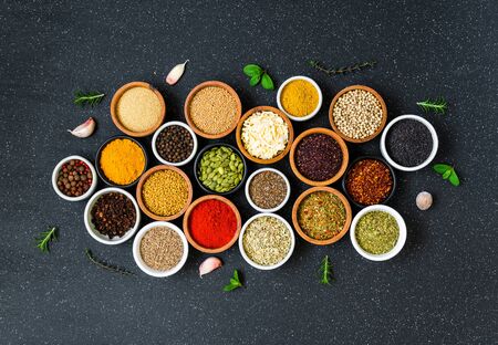 Variety of colorful spices, herbs, and seeds on black stone backgroundの写真素材