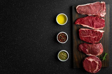 Selection of raw beef meat food steaks against black stone background.の写真素材