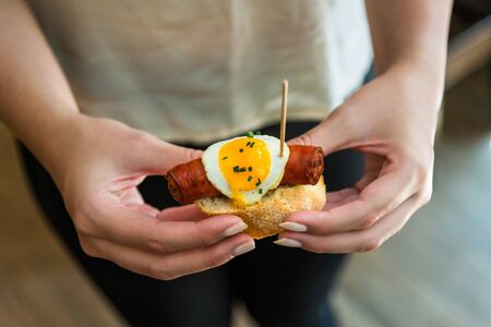 Close up photo of a tapa with Spanish chistorra sausage and quail egg