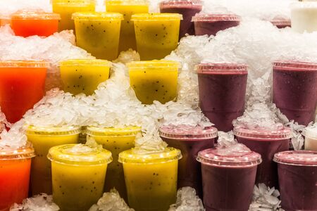 A variety of different colorful fruit smoothies at the farmers market stallの写真素材