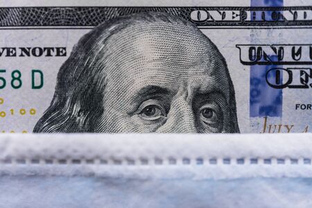 100 US dollars bill with a face mask against coronavirus covid-19 pandemic.