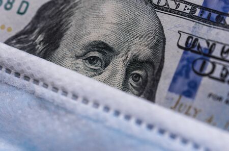 100 US dollars bill with a face mask against coronavirus covid-19 pandemic.の写真素材
