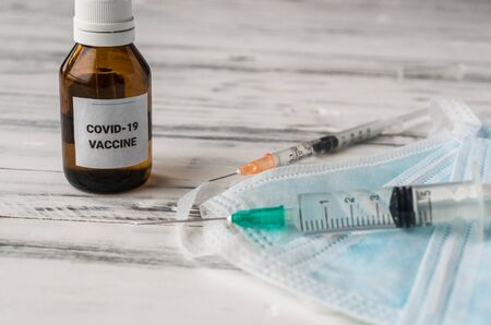 Coronavirus covid-19 vaccine with syringes on the background of face masks.の写真素材