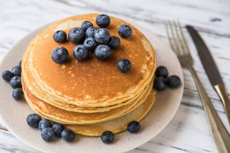 Close up of fluffy pancakes with blueberries against white wooden backgroundの写真素材