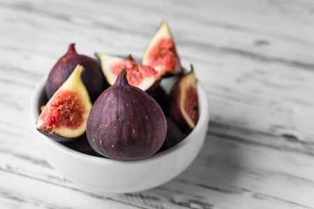 Close up of figs in a bowl against white wooden backgroundの写真素材