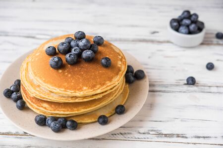 Close up of fluffy pancakes with blueberries against white wooden backgroundの写真素材