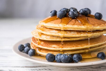 Close up of fluffy pancakes with maple syrup and blueberries.の写真素材