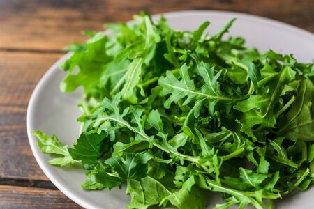 Arugula rocket salad on a plate against wooden background