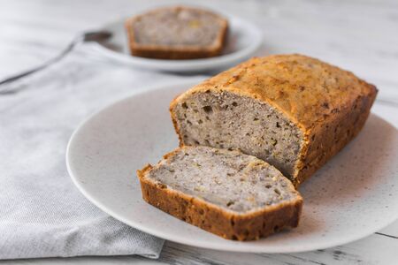 Vegan banana bread loaf cake against white wooden background