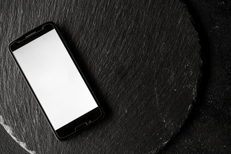 Empty screen of a smartphone with copy space against black slate background.の写真素材