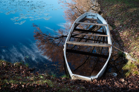 Old wooden boat full of water on lakeの写真素材