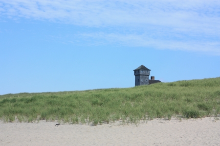 Old lighthouse by the sea with deep blue sky and green grassの写真素材