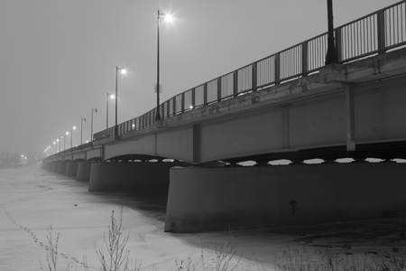 black and whit photo of a bridge in foggy night in winterの写真素材