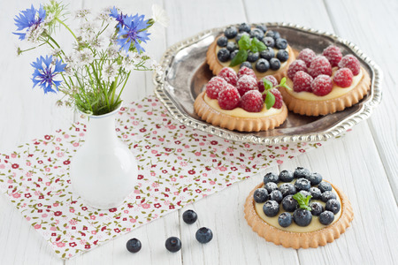 Blueberry and raspberry tartlets on a silver platterの写真素材