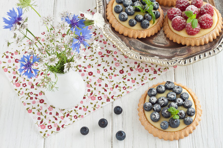 Blueberry and raspberry tartlets on a silver platterの写真素材