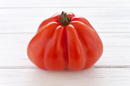 Oxheart tomato on a white wooden boardの写真素材