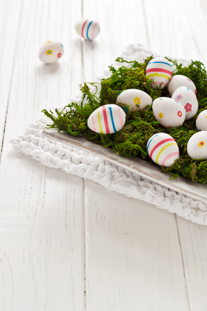 Easter eggs in a bowl on a white knitted tableclothの写真素材