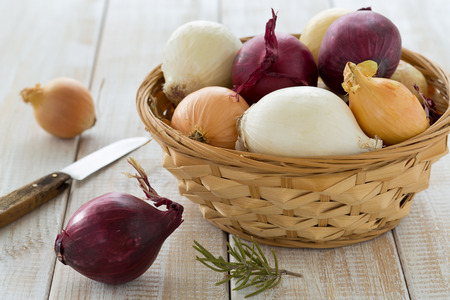 Colorful onions in a basket with a knifeの写真素材