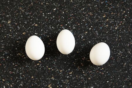 Still life, abstract arrangement with tree eggs lies on black spotted background. New life concept....